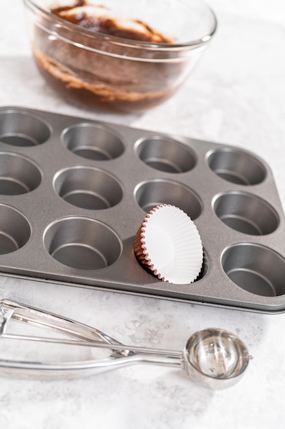 Scooping cupcake batter into the cupcake liners to bake chocolate strawberry cupcakes