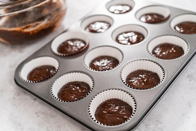 Scooping cupcake batter into the cupcake liners to bake chocolate strawberry cupcakes