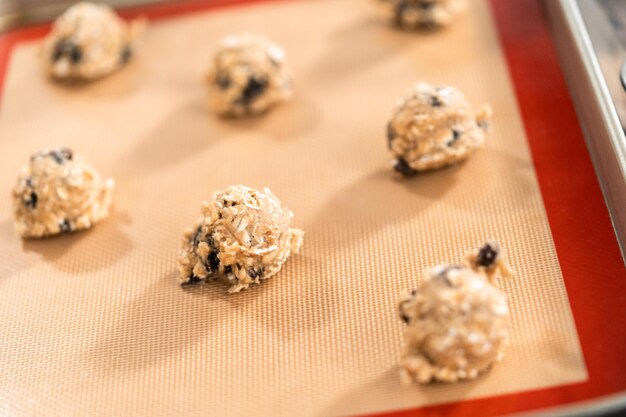 Scoops of cookie dough on a baking cheets to bake chewy oatmeal raisin cookies.