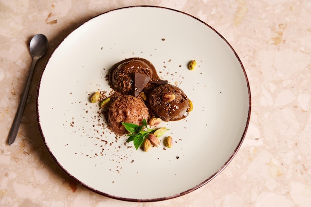 Scoops of healthy raw vegan chocolate sorbet topped with pistachio lemon basil on a serving plate on marble background