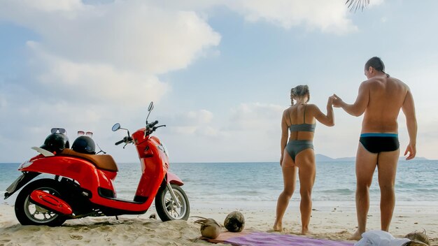 Scooter road trip Mooi stel op rode motor in witte kleren op zandstrand