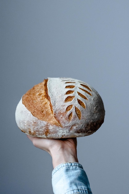 Scoring a bread pattern in the hand of an artisan on a gray background. Crispy unleavened bread