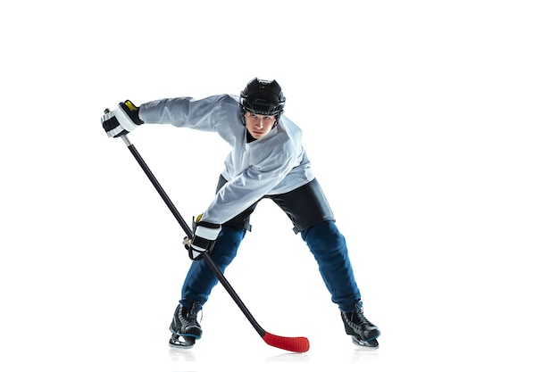 Punteggio. giovane giocatore di hockey maschio con il bastone sul campo di ghiaccio e sfondo bianco. sportivo che indossa attrezzatura e casco che pratica. concetto di sport, stile di vita sano, movimento, movimento, azione.