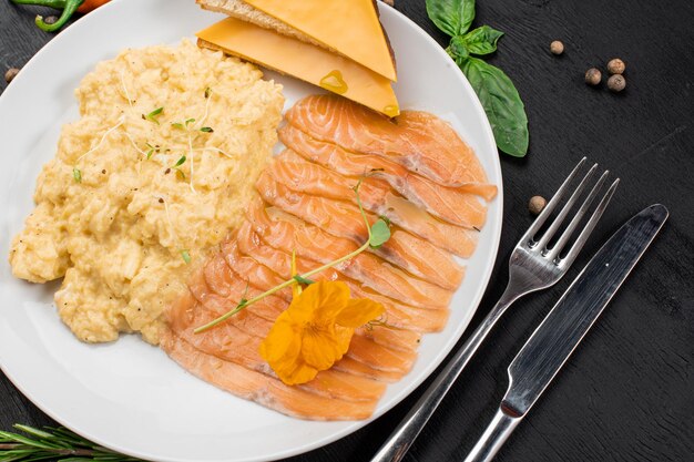 Scramble egg with salmon and cheese sandwich on wooden background