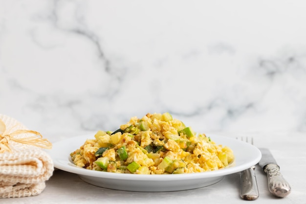 Scrambled egg with zucchini on white small plate