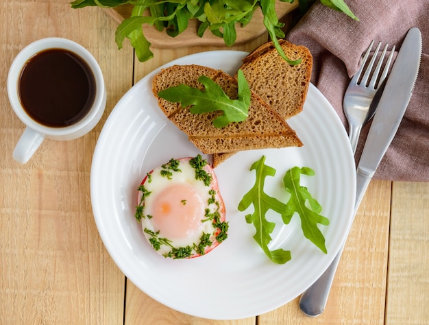 Scrambled eggs, baked in a ring bell pepper, toast, arugula leaves and a cup of coffee. Light breakfast. The top view