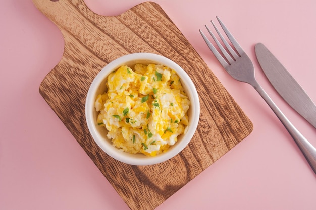 Scrambled eggs on bowl pink background top view