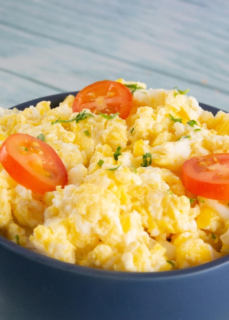 Scrambled eggs on bowl wooden table vertical