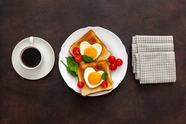 Scrambled eggs in the form of heart on plate with tomatoes, greens and coffee