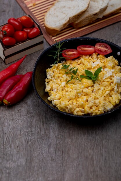 Scrambled eggs in an iron pan on the rustic wooden table