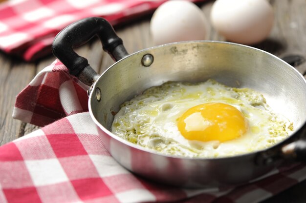 Scrambled eggs in an iron pan on the rustic wooden table