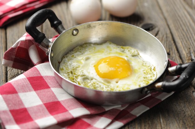 Scrambled eggs in an iron pan on the rustic wooden table