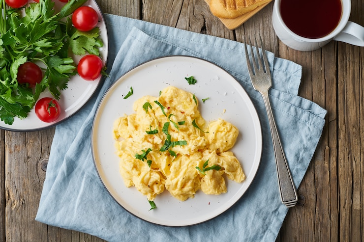 Photo scrambled eggs, omelette, top view. breakfast with pan-fried eggs, tomatoes on old wooden table
