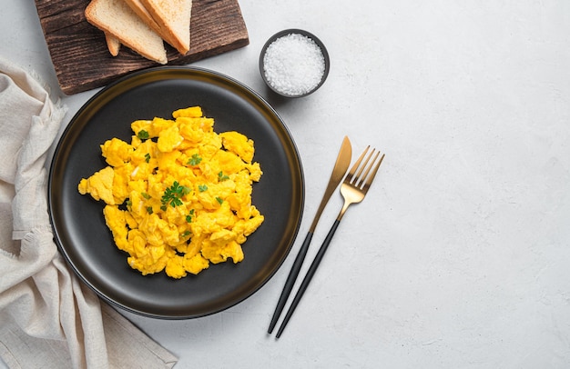 Photo scrambled eggs on a plate with parsley for a healthy breakfast or brunch. top view, copy space.