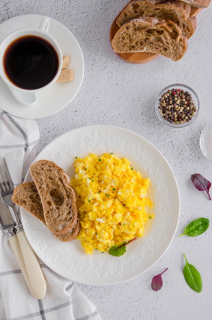 Photo scrambled eggs  on a white plate with rye bread