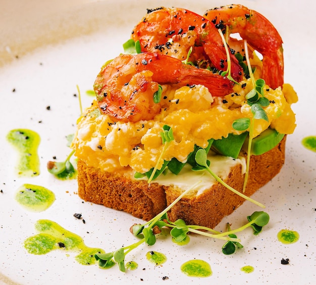 Scrambled eggs with avocado and shrimps on plate