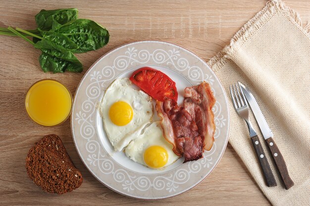 Photo scrambled eggs with bacon, spinach and beans on the plate