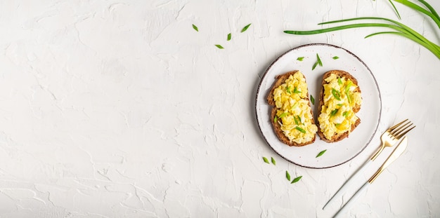 Scrambled eggs with green onion on wheat rye wholemeal crispy bread, homemade, healthy breakfast or brunch