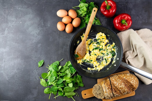 Scrambled eggs with spinach in a pan copy space