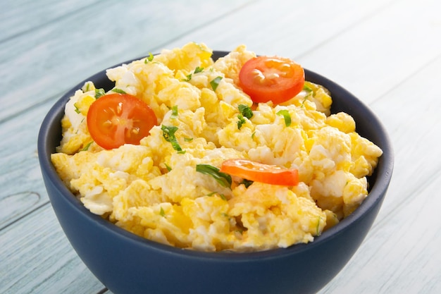 Scrambled eggs with tomatoes on a bowl wooden table