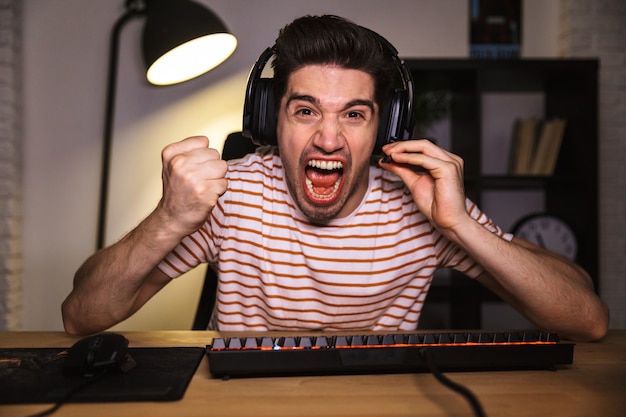 Screaming angry gamer playing video games on computer