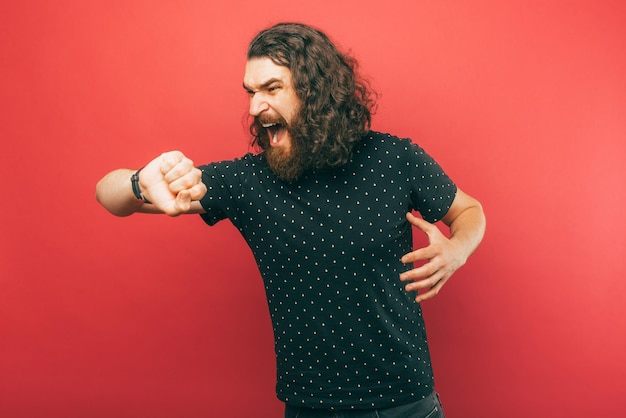 Screaming bearded man is in a hurry while looking at the wrist watch he wears