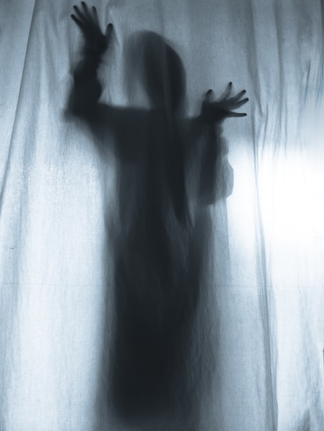 Photo screaming human pressing through fabric curtain as horror background