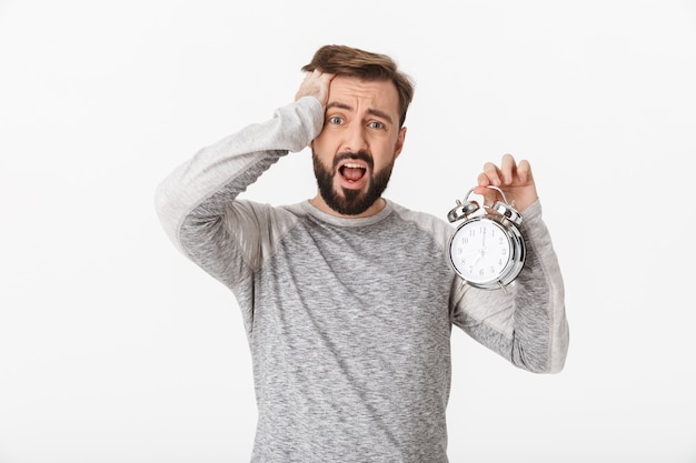 Screaming scared young man holding alarm clock.