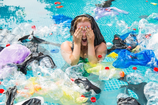Кричащая женщина с полиэтиленовым пакетом над головой в грязном бассейне.