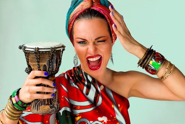 screaming young attractive woman singer in african style with drum on colorful wall