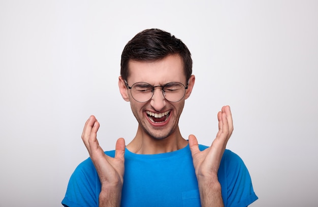 Screaming young white man in a blue T-shirt and glasses.