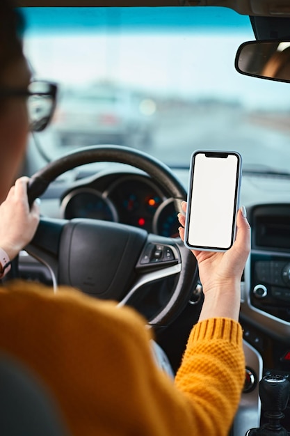차에 탄 여성 운전자의 손에 빈 모형 휴대전화 화면