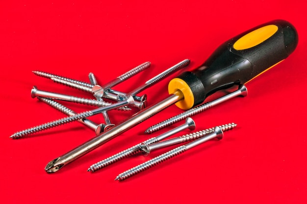 Photo screw driver and screws against a red background