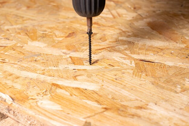 Screw and screwdriver on a chipboard sheet