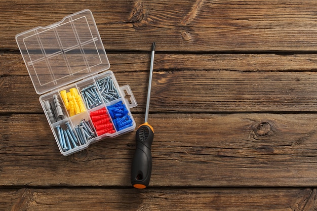 Screwdriver and dowels on dark wooden surface