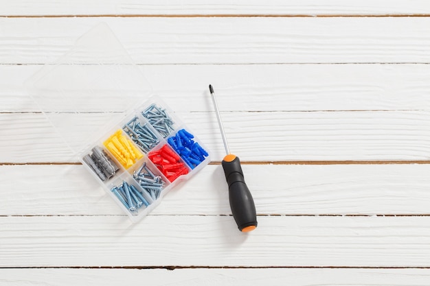 Screwdriver and dowels on white wooden table