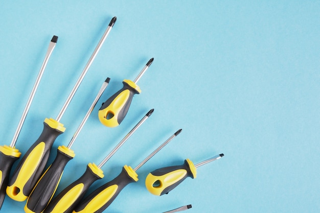 Screwdriver set on a blue background top view copy space many screwdrivers with black and yellow handles