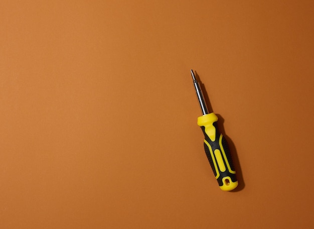 Screwdriver with a rubber handle on a brown background close up