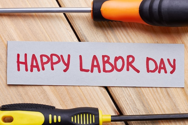 screwdrivers and labour day card. greeting paper on wooden plank. festival for the workers.