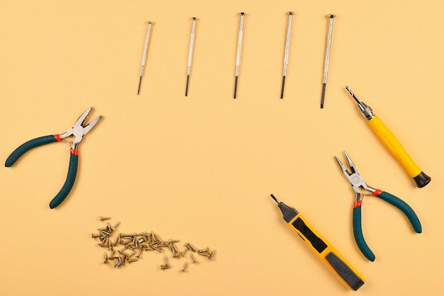 Screwdrivers and pliers on orange background