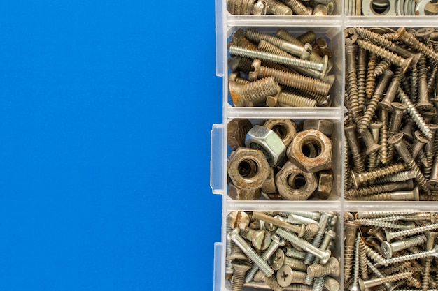 Screws, bolts, nuts and other carpenter stuff in a plastic toolbox (hardware organizer). Flat lay top view with copyspace for text. Stock photo.