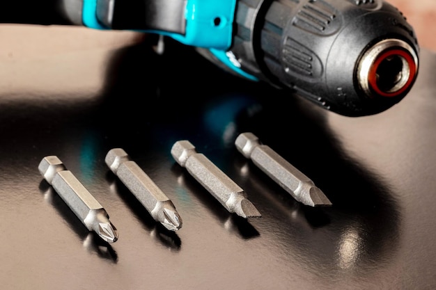 Screws for tightening the screws near the cordless screwdriver on a brown wooden surface