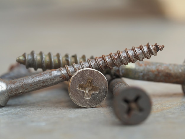 Photo screws with signs of rust lie on a metal background