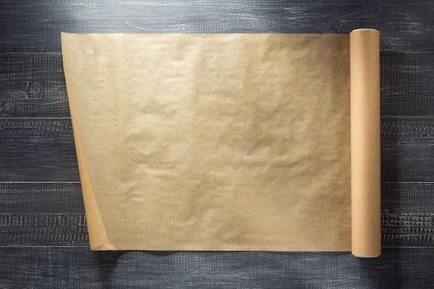 Scroll of brown paper at wooden background texture