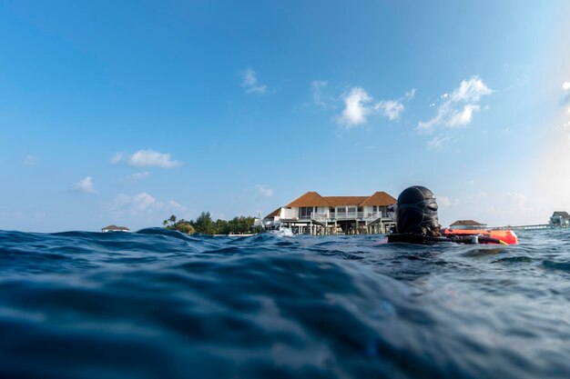 Scuba diver on sea surface near tropical resort overwater bungalow