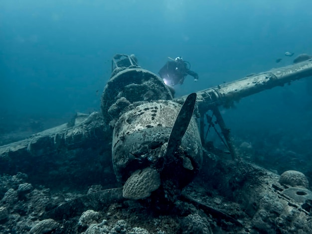 Scuba diver swimming by abandoned airplane in sea