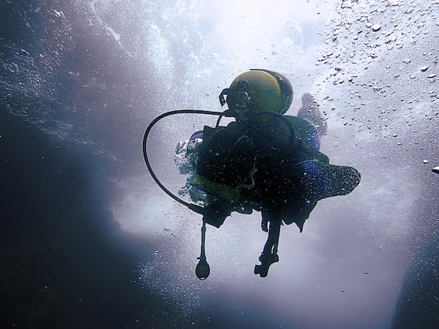 Scuba Diver underwater silhouettes against sun