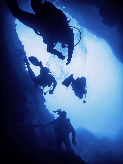 Foto silhouette di subacquei in una grotta sottomarina