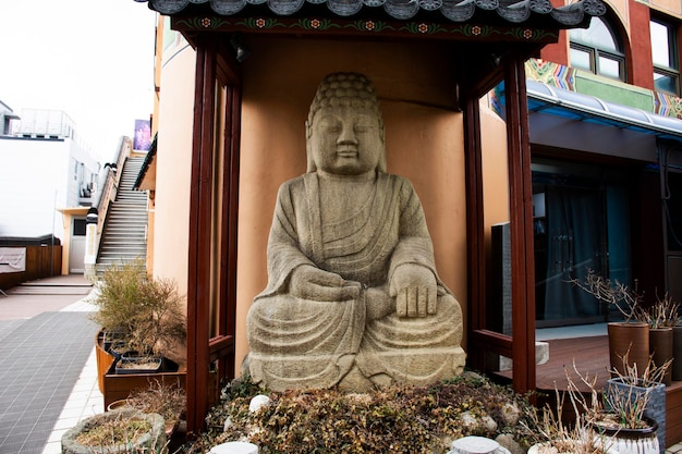 Foto scultura che scolpisce una grande statua di buddha in pietra in stile tibet per i viaggiatori coreani che i viaggiatori visitano e rispettano pregando alla diamond busan tower e al parco yongdusan il 18 febbraio 2023 a busan, corea del sud