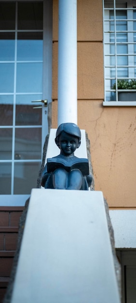 Sculpture of a child reading at the entrance of a house